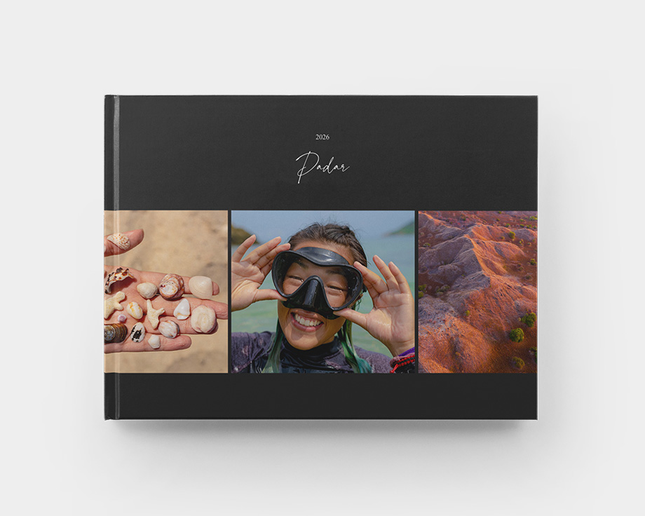 A closed landscape hardcover photo book with summer images on the cover