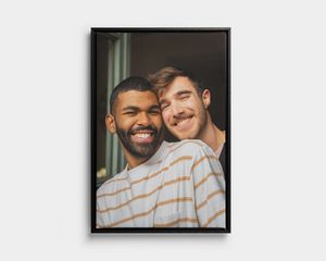 Black framed portrait canvas print of two smiling men.